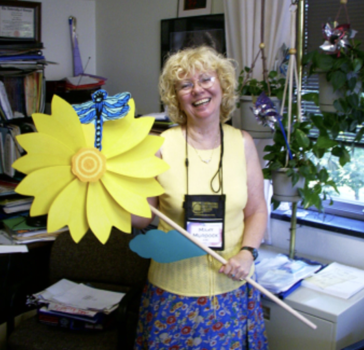 Mary C. Murdock smiling and holding a large plastic sunflower 