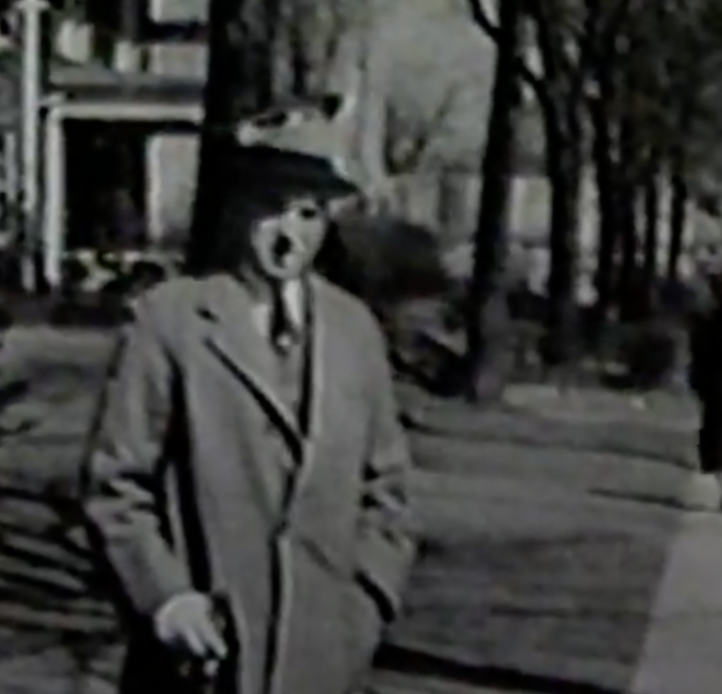 Black and white image of a man standing by the sidewalk 