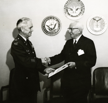 Older Osborn shaking hands with a leader of the Armed Forces 