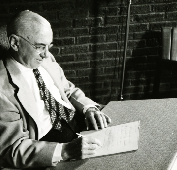 Older Osborn writing at his desk 